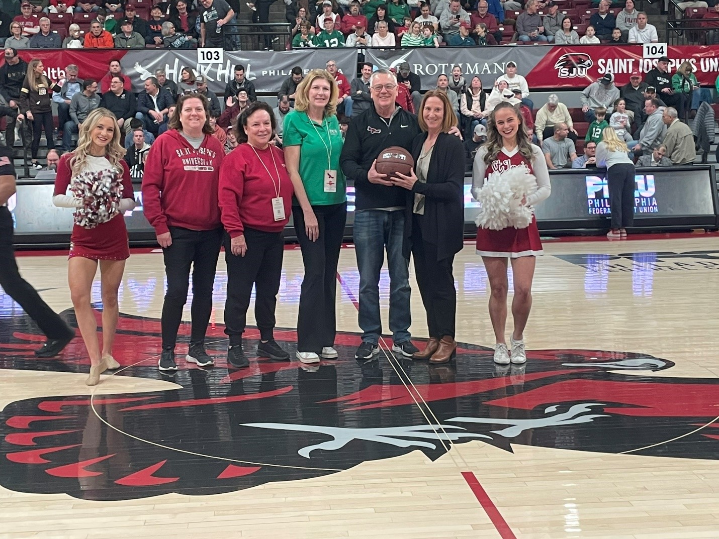 Accepts the game ball from Jill Bodensteiner