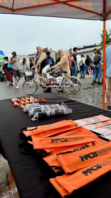 PFCU stand and woman on bike.