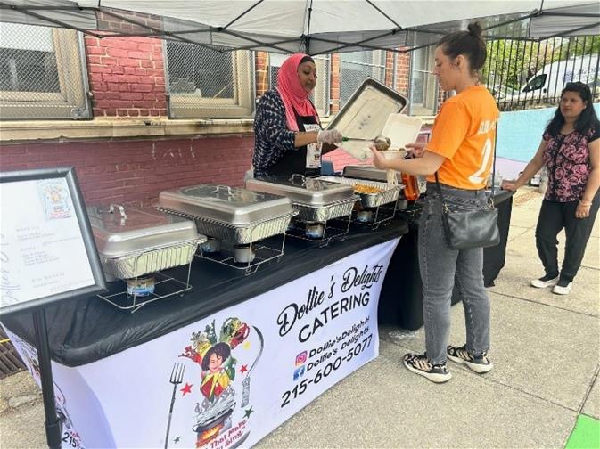 Women at Dollie's Delights Catering table getting food.