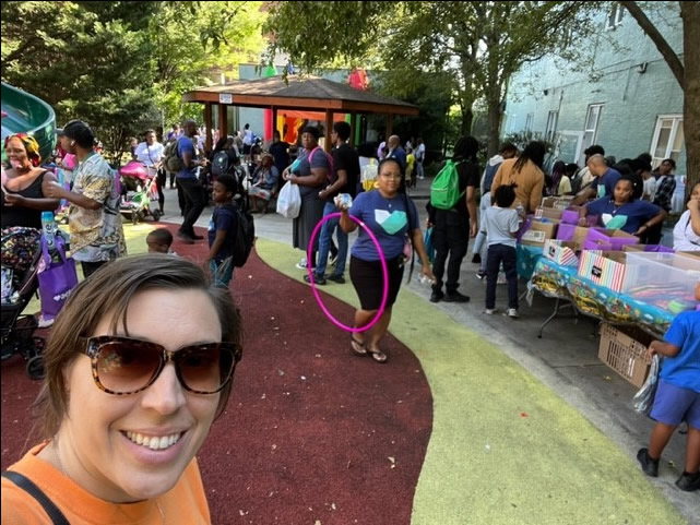 Woman taking a selfie at Back-to-School Bash with people behind her.