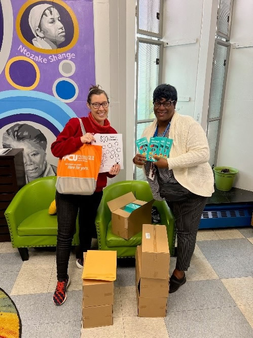 Two women holding coloring books and colored pencils.
