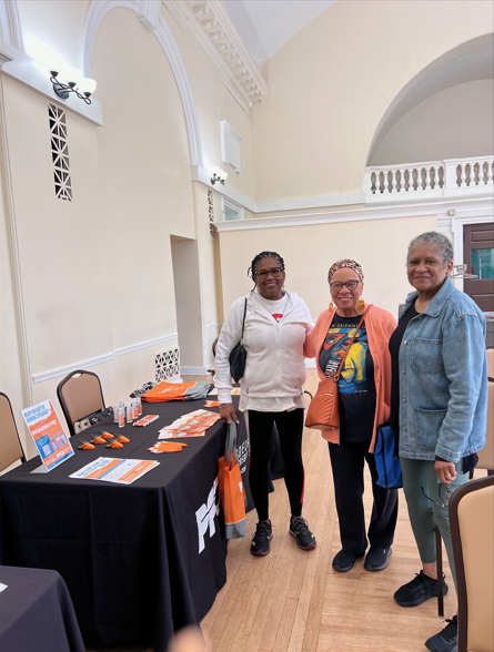PFCU Business Development Specialist Yorkenia Gomez distributing literature and free giveaways, posing with others.