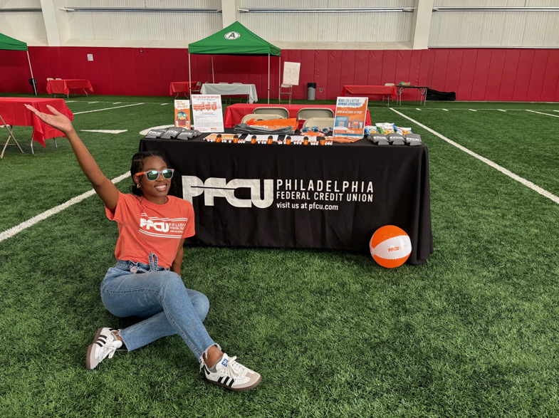 Yahné Jackson, PFCU's Financial Educator and Community Relations Specialist in front of a PFCU booth.
